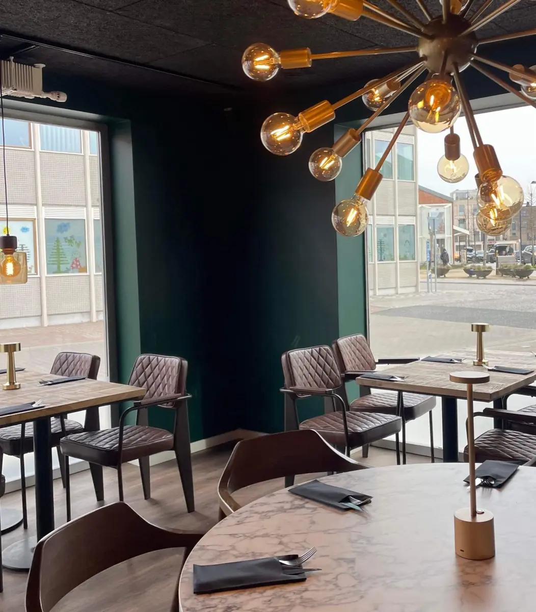 Tables by the window overlooking Hovedgaden, with a brass chandelier